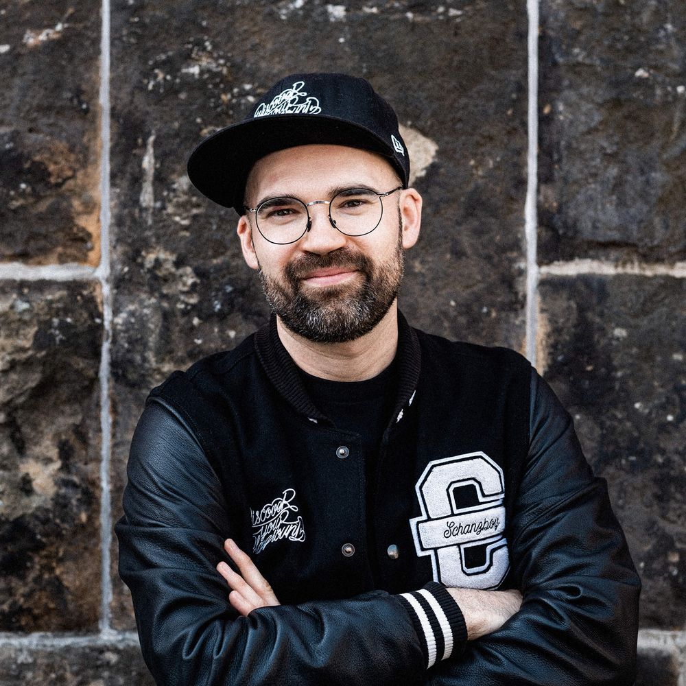 Auf dem Bild ist Andreas zu sehen. Er trägt eine schwarze Cromatics-Jacke und ein Cap.