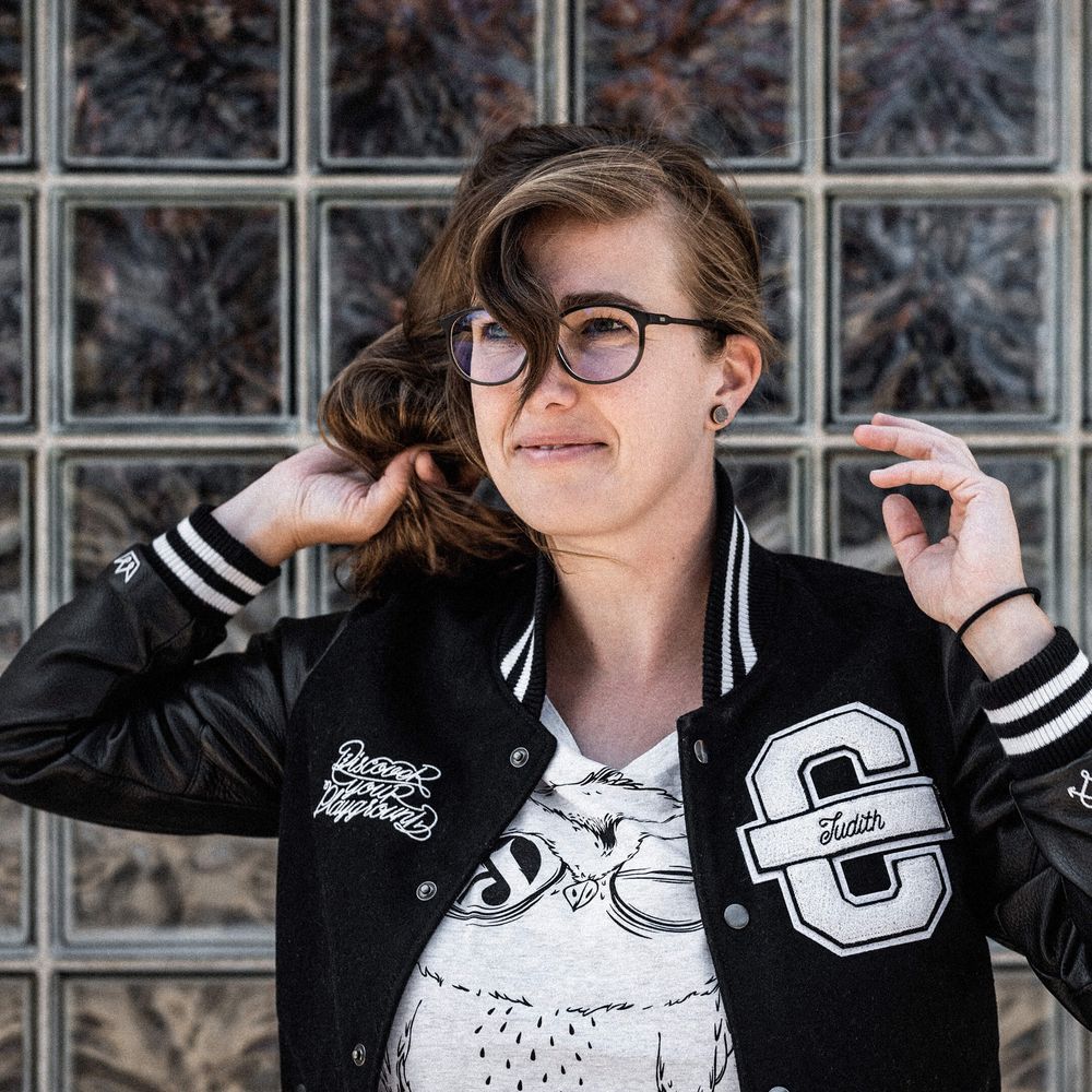 Auf dem Bild ist Judiht zu sehen. Sie trägt eine schwarze Cromatics-Jacke und schaut nach links.