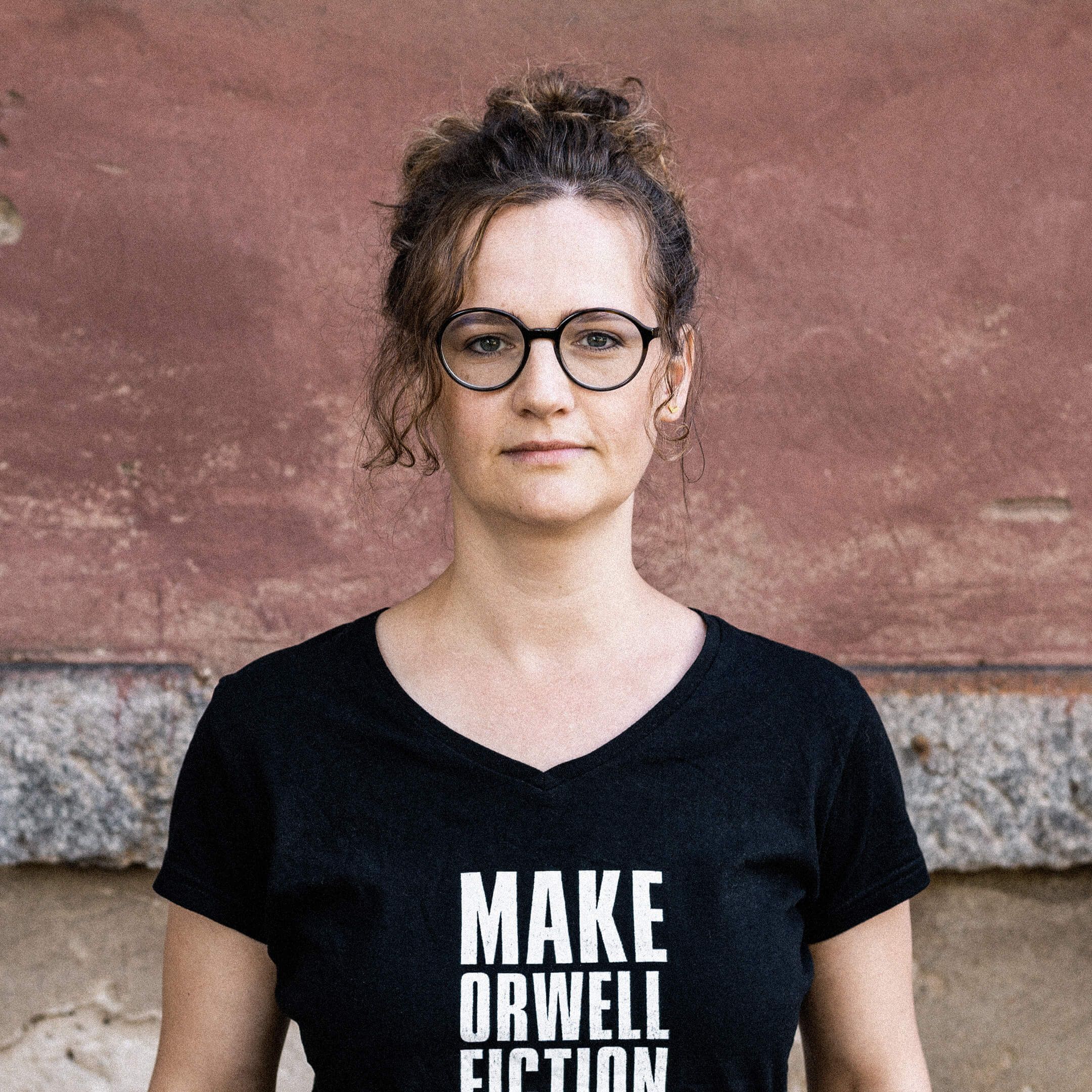 Hier ist Nora zu sehen. Sie trägt ein schwarzes Shirt mit der Aufschrift “Make Orwell fiction again”