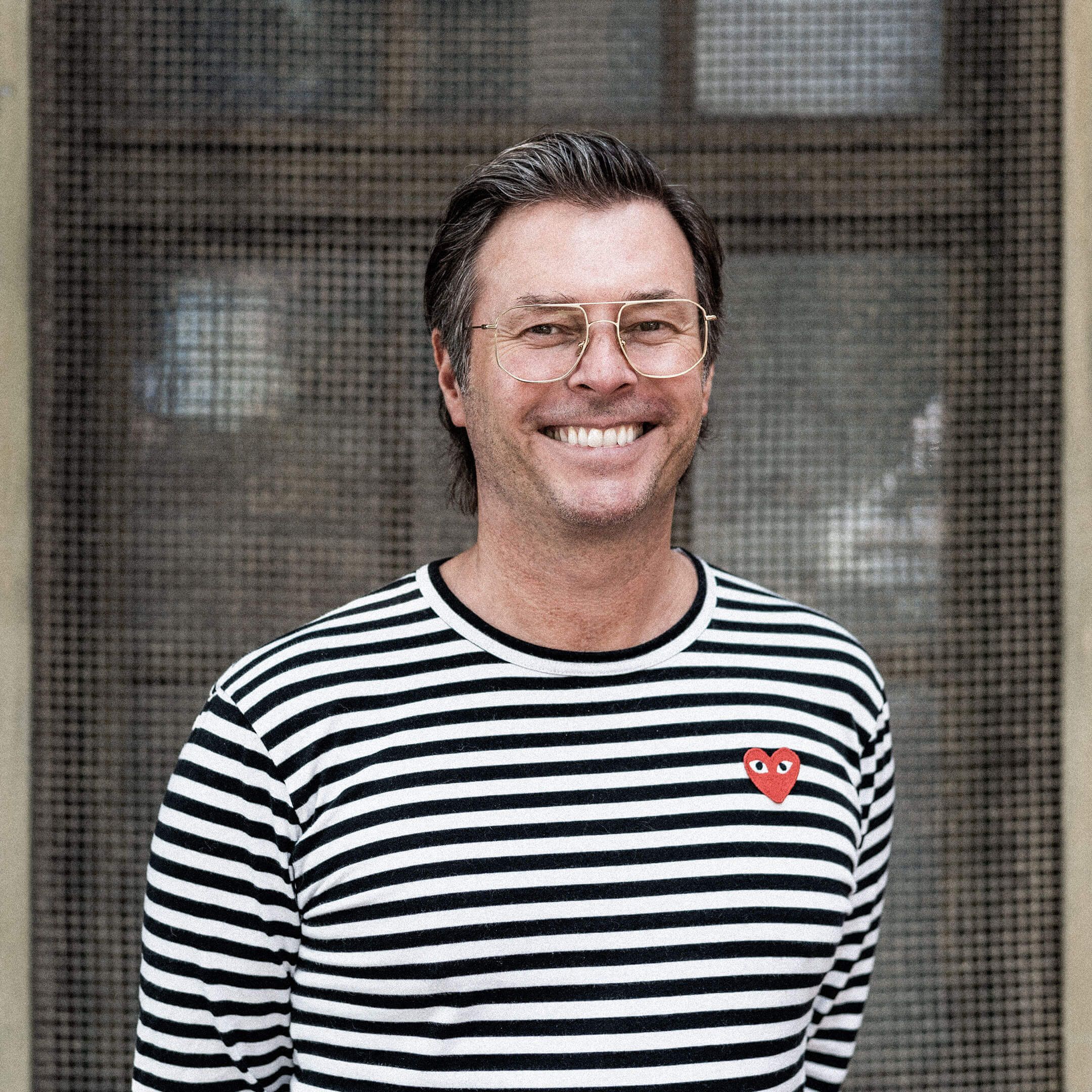 Auf dem Bild ist Sören zu sehen. Er trägt ein weißes/scharz gestreiftes Shirt und lächelt.