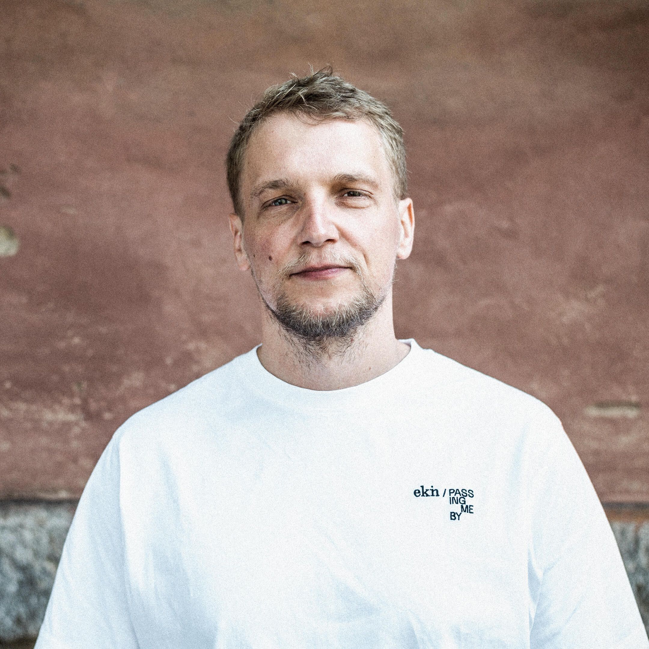 Auf dem Bild ist Stolle zu sehen. Er trägt ein weißes Shirt und lächelt leicht.